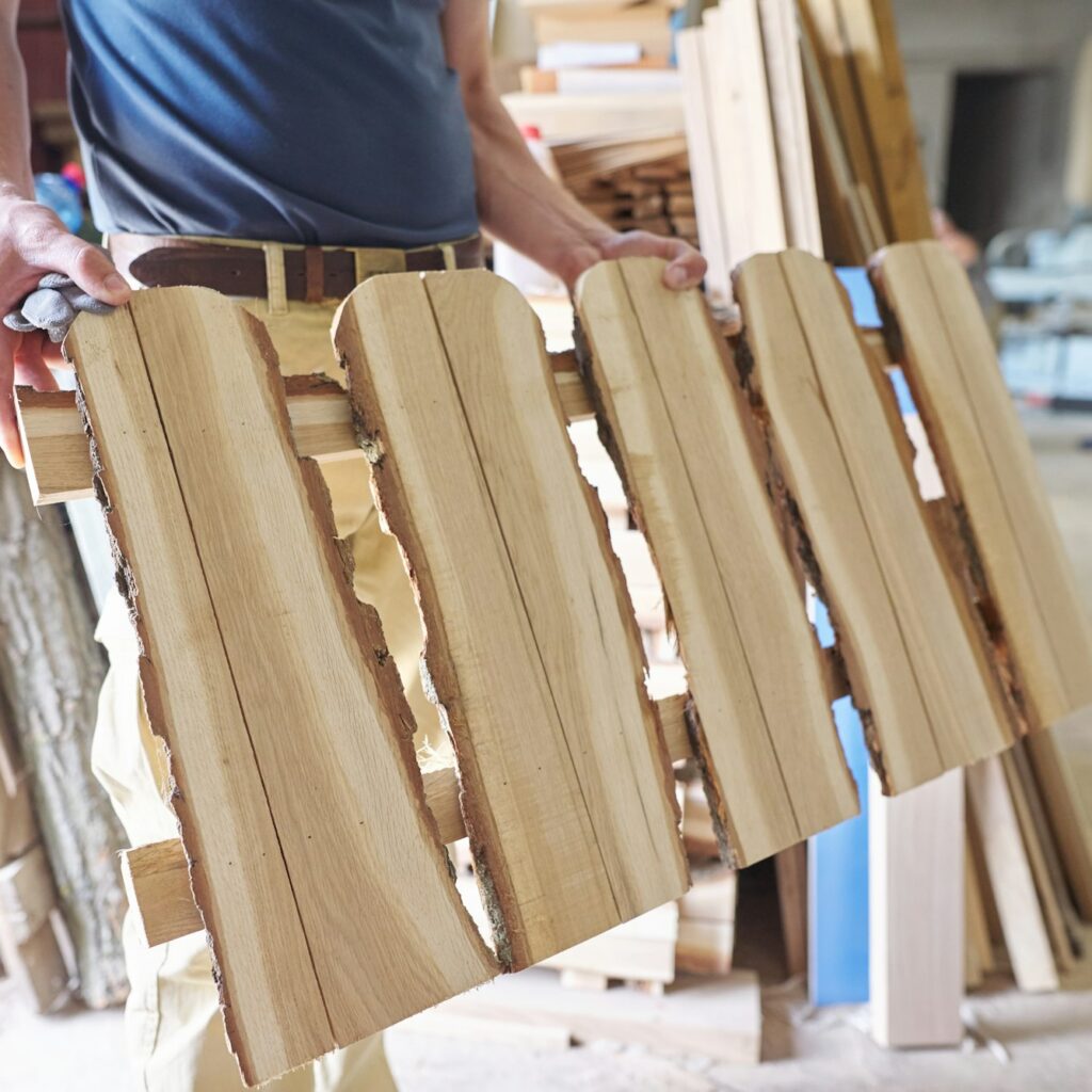 Male carpenter showing wooden fence in rustic style in carpentry workshop